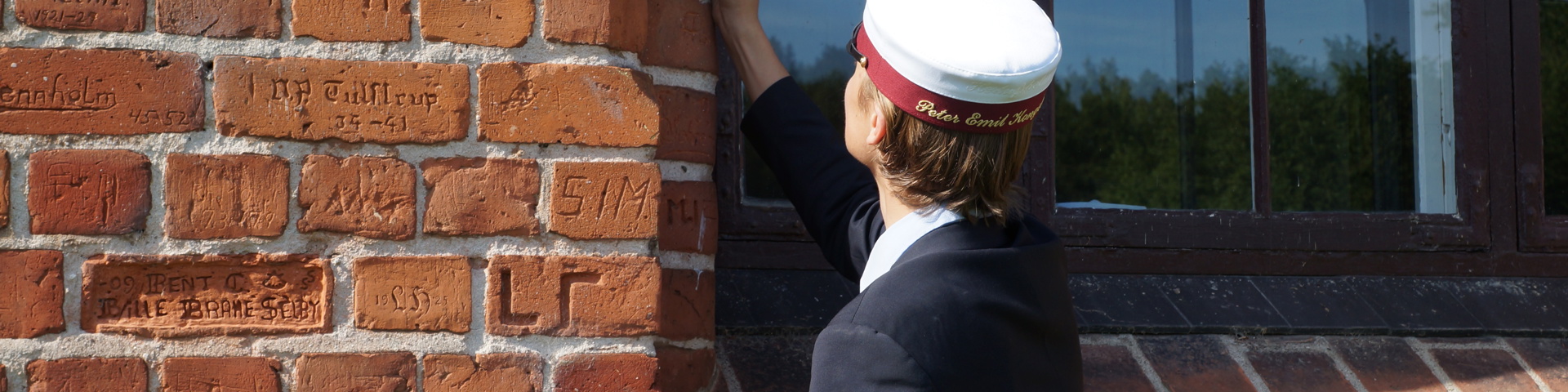 Student Fra Herlufsholm skriver sit navn i murstenene ved Mygningen